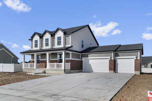 View of front of property with a porch, fence, concrete driveway, a garage, and brick siding