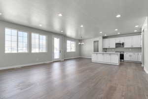 Kitchen featuring tasteful backsplash, wood finished floors, open floor plan, appliances with stainless steel finishes, and light countertops