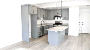 Kitchen with a kitchen island, gray cabinets, and appliances with stainless steel finishes