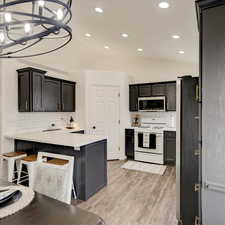 Kitchen with hanging light fixtures, backsplash, vaulted ceiling, and stainless steel appliances