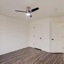 Unfurnished bedroom featuring dark hardwood / wood-style floors and ceiling fan