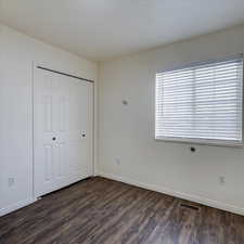 Unfurnished bedroom with dark hardwood / wood-style flooring and a closet