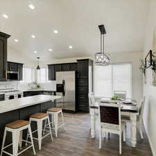 Kitchen with vaulted ceiling, decorative light fixtures, backsplash, dark hardwood / wood-style flooring, and stainless steel appliances