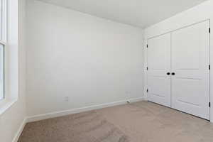 Unfurnished bedroom with light colored carpet and a closet