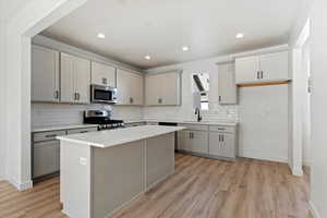 Kitchen featuring a kitchen island, appliances with stainless steel finishes, gray cabinets, and sink