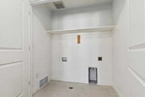 Washroom with hookup for an electric dryer, hookup for a washing machine, and light tile patterned floors