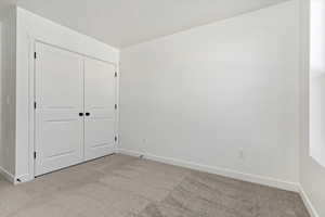 Unfurnished bedroom with light carpet and a closet