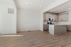 Kitchen with stainless steel appliances, a center island, gray cabinetry, and light wood-type flooring