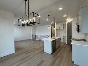 Kitchen featuring sink, decorative light fixtures, light hardwood / wood-style flooring, an island with sink, and stainless steel appliances