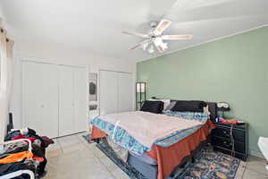 Tiled bedroom featuring multiple closets and ceiling fan