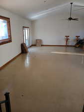 Empty room with vaulted ceiling, baseboards, and a ceiling fan