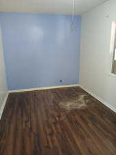 Spare room featuring baseboards, wood finished floors, and a textured ceiling