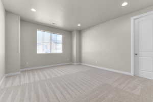 Unfurnished room featuring light colored carpet and a textured ceiling