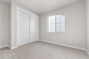 Unfurnished bedroom with light carpet and a closet