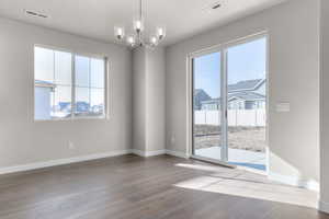 Unfurnished room featuring an inviting chandelier and light hardwood / wood-style flooring