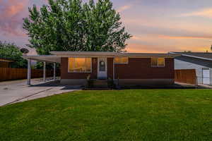 View of front of house with a carport and a yard