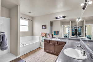 Bathroom with tile patterned flooring, vanity, a textured ceiling, and a tub to relax in