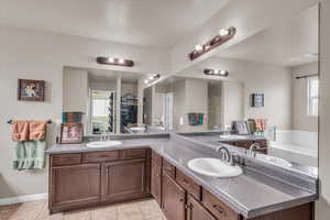 Bathroom with vanity, tile patterned floors, and a tub to relax in