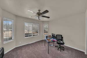 Carpeted office with a textured ceiling and ceiling fan