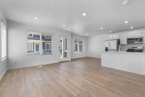 Kitchen with white cabinetry, light hardwood / wood-style flooring, stainless steel appliances, and plenty of natural light