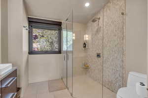 Bathroom featuring walk in shower, tile patterned floors, toilet, and vanity