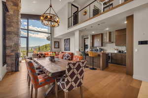 Dining area with a notable chandelier, light wood-type flooring, and a high ceiling