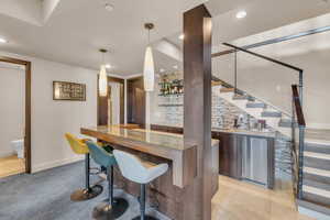 Bar featuring pendant lighting, backsplash, stainless steel fridge, and light tile patterned floors