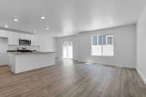 Kitchen featuring stainless steel appliances, white cabinetry, a center island with sink, and laminate