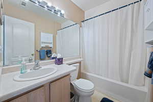 Full bathroom featuring vanity, shower / bath combo, and toilet