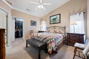 Carpeted bedroom with a walk in closet, lofted ceiling, ceiling fan, and a closet