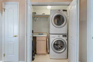 Washroom featuring cabinets and stacked washing maching and dryer