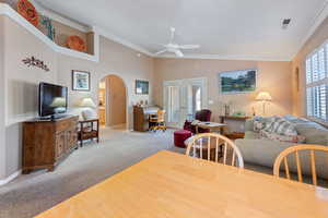 Dining area with light carpet, vaulted ceiling, ornamental molding, and ceiling fan