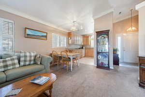 Carpeted living room featuring an inviting chandelier, ornamental molding, and a textured ceiling