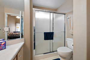 Bathroom with toilet, vanity, and a shower with shower door