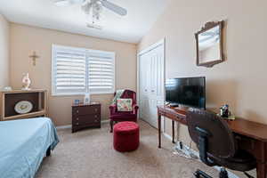 Carpeted bedroom featuring vaulted ceiling, a closet, and ceiling fan