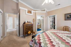 Carpeted bedroom with ensuite bathroom, lofted ceiling, a walk in closet, ceiling fan, and a closet