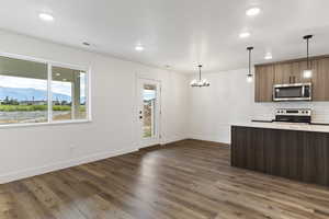 Kitchen with decorative light fixtures, backsplash, a chandelier, dark hardwood / wood-style flooring, and stainless steel appliances