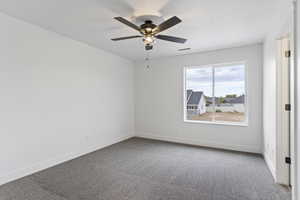 Empty room with ceiling fan and carpet floors