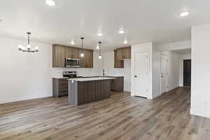 Kitchen featuring pendant lighting, light wood-type flooring, stainless steel appliances, and a kitchen island