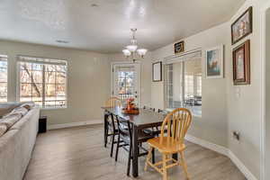 Dining room featuring a notable chandelier, light hardwood / wood-style flooring, and a textured ceiling