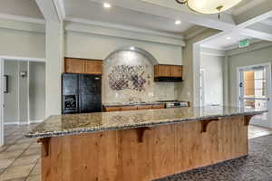 Clubhouse: Kitchen with stainless steel electric stove, a kitchen breakfast bar, dark stone counters, decorative backsplash, and black fridge with ice dispenser