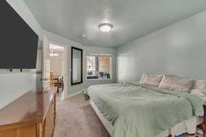 Master Bedroom: Carpeted bedroom featuring an inviting chandelier and a textured ceiling