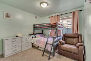 Bedroom with light colored carpet and a textured ceiling