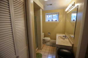 Bathroom featuring vanity,  toilet, and walk-in shower