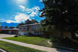 View of front of house featuring a garage, a mountain view, and a front lawn