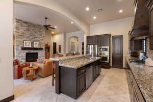 Kitchen with premium range hood, sink, a breakfast bar area, stainless steel appliances, and a kitchen island with sink