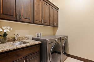 Laundry room with cabinets, sink, light tile patterned floors, and washing machine and clothes dryer