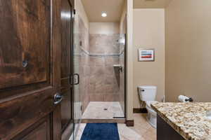 Bathroom with tile patterned floors, vanity, toilet, and a shower with shower door