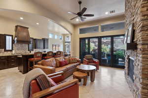 Tiled living room featuring french doors, ceiling fan, a fireplace, and a high ceiling