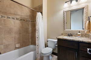 Full bathroom with vanity, shower / tub combo, tile patterned flooring, and toilet